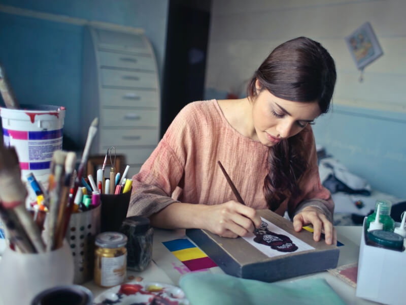 A person concentrating as they create a watercolour painting